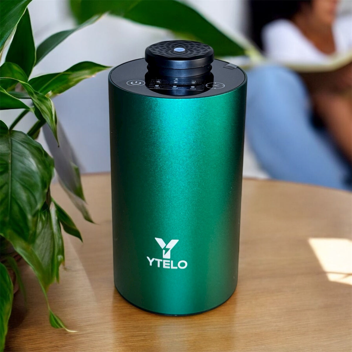 YTELO Emerald Green waterless essential oil diffuser displayed on a wooden table in a softly blurred indoor setting.